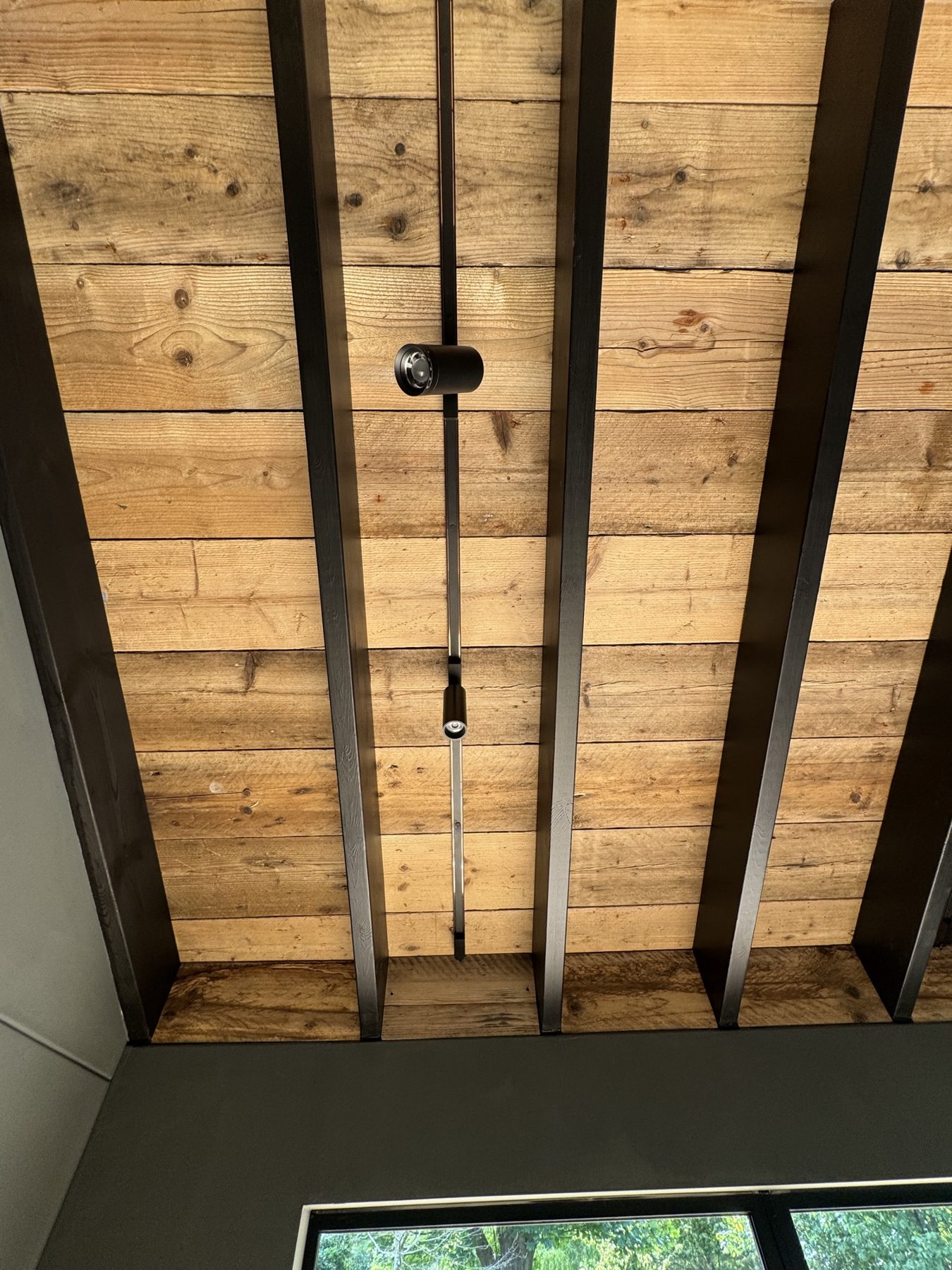 Timber boarded ceiling between dark steel beams – USFEW carpentry, Kent